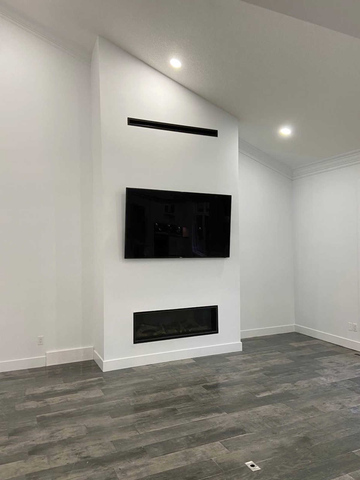 Interiors. Recreation room, tv room, or living room with hardwood flooring, white walls and a fireplace. A modern home interior design and renovation, drywall, flooring, doors, stairs, painting and more. A London Ontario home renovation project by Brothers Construction 3 Inc.